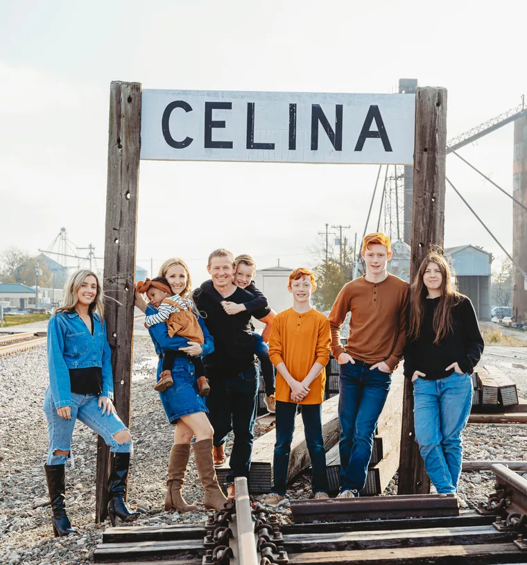 David Solomon with his wife and six children under the Celina, Texas railroad sign